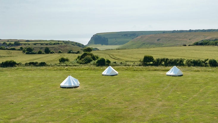 An aerial view of the bell tents at Weston Farm Campsite and the coast beyond, Dorset